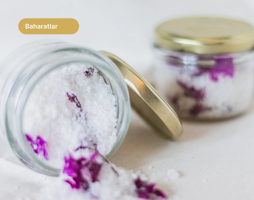 Yumuşak nötr arka planda doğal banyo tuzu ve kurutulmuş pembe çiçek yaprakları dolu minimalist cam kavanoz.