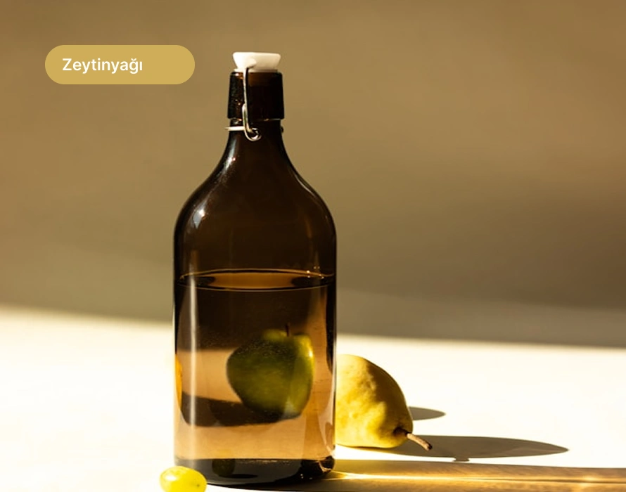 Zeytin yapraklarıyla birlikte koyu ahşap yüzeyde doğal zeytinyağı dolu rustik cam şişe.